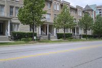 an empty street and some buildings on both sides of the road, with the green grass between the two trees