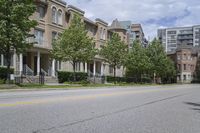 an empty street and some buildings on both sides of the road, with the green grass between the two trees