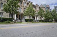 an empty street and some buildings on both sides of the road, with the green grass between the two trees