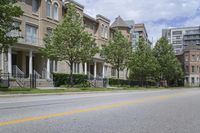 an empty street and some buildings on both sides of the road, with the green grass between the two trees