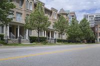 an empty street and some buildings on both sides of the road, with the green grass between the two trees