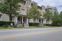 an empty street and some buildings on both sides of the road, with the green grass between the two trees