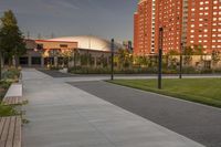 a city street surrounded by grass and tall buildings at the end of a street there is a paved pathway in front of the building