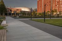 a city street surrounded by grass and tall buildings at the end of a street there is a paved pathway in front of the building