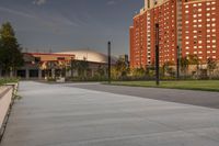 a city street surrounded by grass and tall buildings at the end of a street there is a paved pathway in front of the building