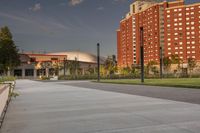 a city street surrounded by grass and tall buildings at the end of a street there is a paved pathway in front of the building