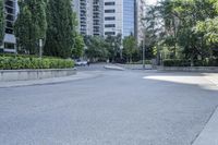 a car driving down an empty street lined with tall buildings and trees in the background