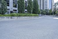 a car driving down an empty street lined with tall buildings and trees in the background