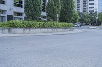 a car driving down an empty street lined with tall buildings and trees in the background