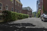 a car is parked on a paved side walk near a tree and brick building on the opposite side