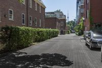 a car is parked on a paved side walk near a tree and brick building on the opposite side