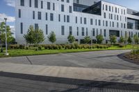 a city street surrounded by grass and tall buildings at the end of a street there is a paved pathway in front of the building