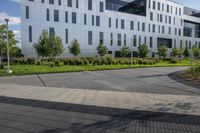 a city street surrounded by grass and tall buildings at the end of a street there is a paved pathway in front of the building