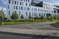 a city street surrounded by grass and tall buildings at the end of a street there is a paved pathway in front of the building