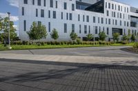 a city street surrounded by grass and tall buildings at the end of a street there is a paved pathway in front of the building