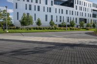 a city street surrounded by grass and tall buildings at the end of a street there is a paved pathway in front of the building