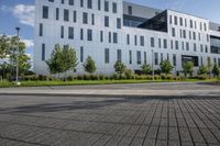 a city street surrounded by grass and tall buildings at the end of a street there is a paved pathway in front of the building