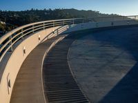 a set of stairs sitting on top of a slope near trees and hills under a clear blue sky