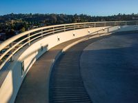 a set of stairs sitting on top of a slope near trees and hills under a clear blue sky