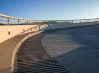 a set of stairs sitting on top of a slope near trees and hills under a clear blue sky