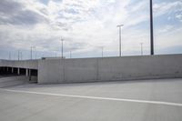 an empty parking lot with two cars parked and lights on poles nearby it in an enclosed parking lot