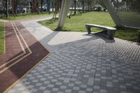 a bench is sitting in the middle of a path near a building and trees and grass