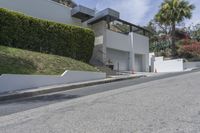 a person riding a motorcycle on the side of a road next to a white building