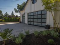 a plant garden in front of the garage is near flowers and plants with potted purples