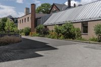 there is a skateboard that is in the driveway near a building and trees on the side