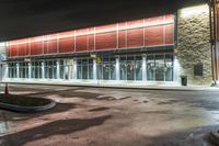 the entrance and parking lot of an airport at night with lights shining off of the windows