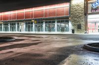 the entrance and parking lot of an airport at night with lights shining off of the windows