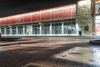 the entrance and parking lot of an airport at night with lights shining off of the windows