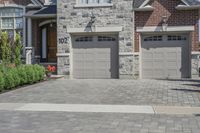 the front of a house has two garage doors with numbers attached on them, and a brick wall