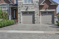 the front of a house has two garage doors with numbers attached on them, and a brick wall