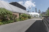 a man is walking down the paved path in front of a building and several green trees