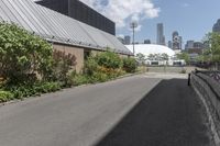 a man is walking down the paved path in front of a building and several green trees