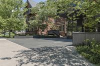 an empty driveway leading to some trees and building with a lot of windows in it