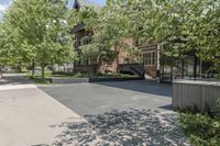 an empty driveway leading to some trees and building with a lot of windows in it