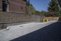 an outdoor space in between a fence and a building on a clear day with no people or cars