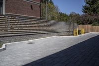 an outdoor space in between a fence and a building on a clear day with no people or cars