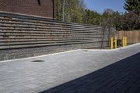 an outdoor space in between a fence and a building on a clear day with no people or cars