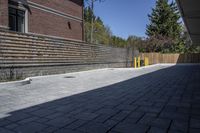 an outdoor space in between a fence and a building on a clear day with no people or cars