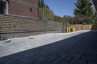 an outdoor space in between a fence and a building on a clear day with no people or cars