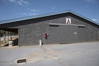 a barn that is gray with no windows and door open with the name a written on the side