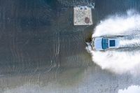 a boat traveling on the water near a sidewalk and concrete structure in the water's wake