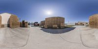 a street with several boxes of logs in the front and behind them a truck, trailer, and barn