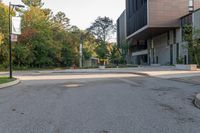 an empty street with trees and buildings in the background and a stop sign on a pole with no people walking