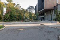 an empty street with trees and buildings in the background and a stop sign on a pole with no people walking