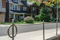 a row of houses and a fence line a street with a parking meter in the foreground