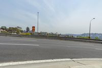 an intersection of a street with some buildings and mountains in the background along the highway